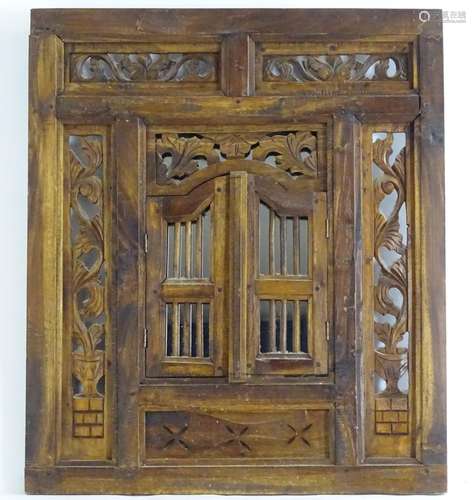 A Middle Eastern carved wall panel with pierced detail and central mirror behind two arched doors.