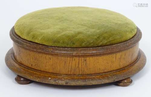 A late 19thC footstool with a circular overstuffed top above a moulded frame and four squat bun