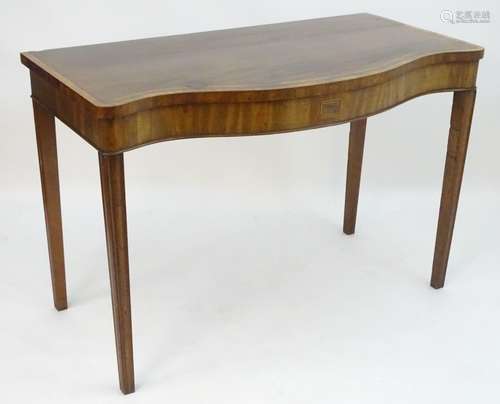 An early 19thC mahogany serving table with a serpentine shaped front, crossbanded top and having