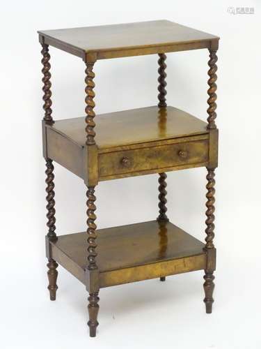 An early 19thC walnut three tier whatnot having four barley twist supports and a single central