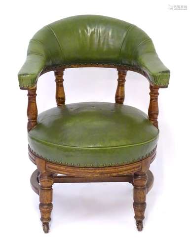 C.1900 oak swivel armchair / captains chair with a shaped green leather upholstered backrest and