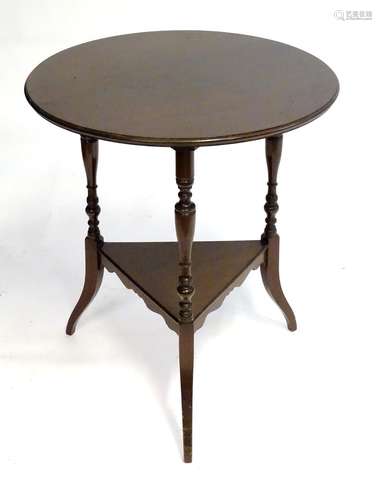 An Aesthetic movement mahogany table with a circular top above three turned supports and splayed