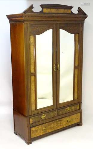 An early 20thC Art Nouveau style walnut wardrobe, with a moulded pediment above a dentil moulded