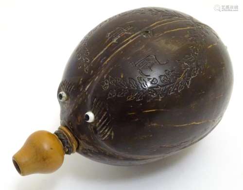 A 19thC carved coconut 'bugbear' Napoleonic flask, with a turned boxwood spout, carved with gothic