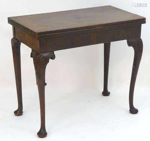 An 18thC mahogany card table / tea table with a rectangular top above cabriole legs with carved