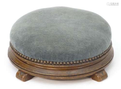 A Victorian mahogany footstool with a circular upholstered top studded detail above four shaped