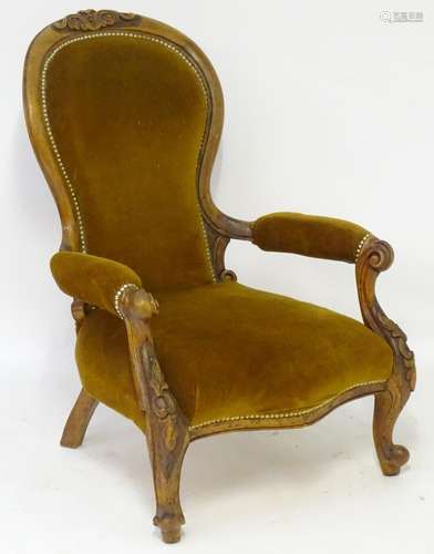 A late 19thC mahogany open armchair with carved cresting rail above a spoon back and swept arms,