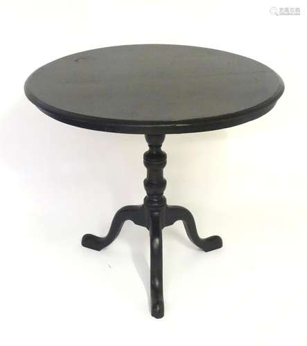 A 19thC ebonised tripod table with a circular top above a turned tapering stem and three cabriole