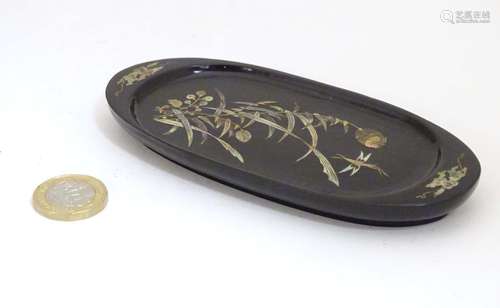 An oval lacquered pin dish with inlaid abalone decoration depicting a stylised dragonfly with