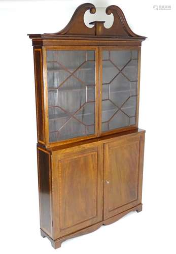 A 19thc mahogany bookcase with a swans neck pediment having moulded roundel decoration and marquetry