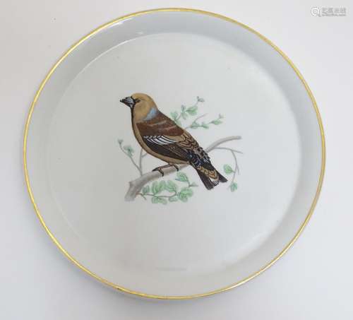 A French L Lourioux Le Faune plate with a gilt rim decorated with a hawfinch bird on a branch.