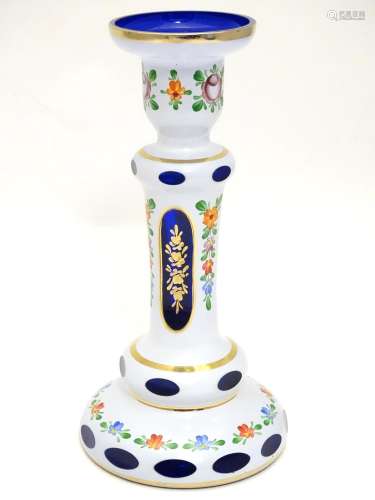 An early 20thC Bohemian blue glass candlestick, overlaid with white base, gilt banding and floral