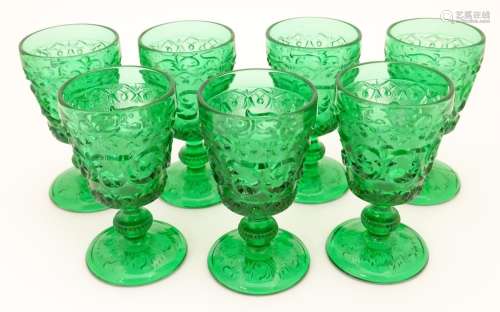 A set of 7 vintage green glass pedestal glasses with moulded decoration . Approx 4