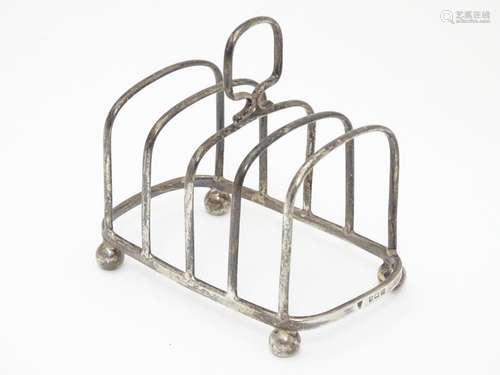 A Silver four division toast rack raised on four bun feet. Hallmarked Birmingham 1923 maker