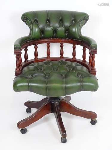 A late 20thC captains chair with deep buttoned leather upholstery, turned finial supports and having