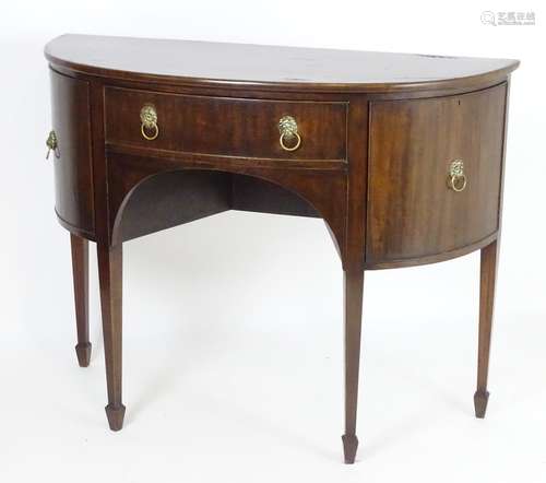 An early 20thC mahogany demi lune sideboard with a single short drawer flanked by cupboards with