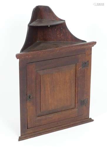 A late 18thC oak corner cupboard with shaped graduated shelves above a single door and wrought