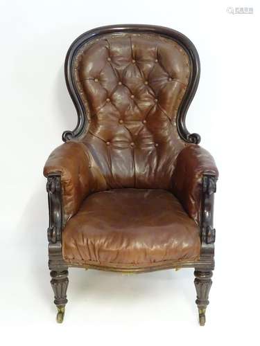 A mid / late 19thC spoon back armchair with a moulded surround and a deep buttoned leather backrest,