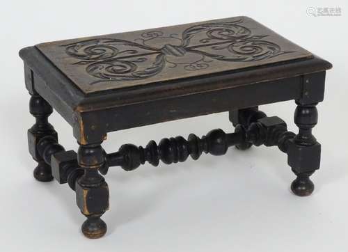 An early 20thC footstool with a carved top above four turned legs united by a H-stretcher. 13