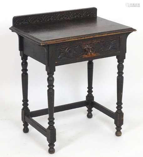 A late 19thC oak side table with a shape upstand above a moulded top and frieze drawer with carved