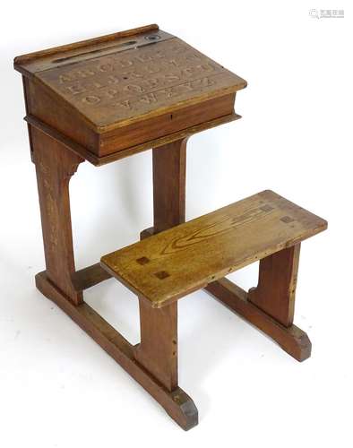 An early 20thC school desk and seat with a liftable slope, the slope having painted alphabet