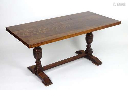 An early / mid 20thC oak draw leaf dining table with a rectangular top above two cup and cover