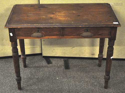 A pine two drawer desk, flared top cast metal handles to front on turned legs,