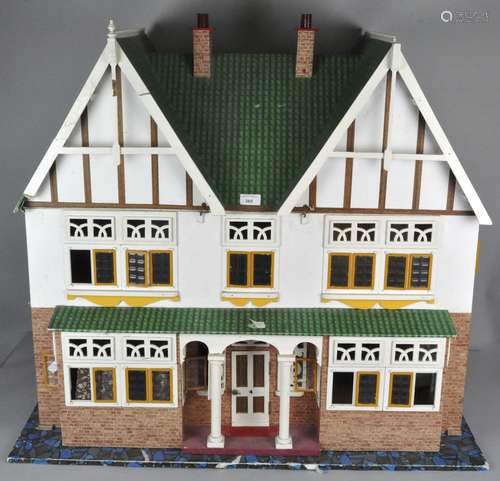 A large dolls house with tiled roof and opening front, with some contents,