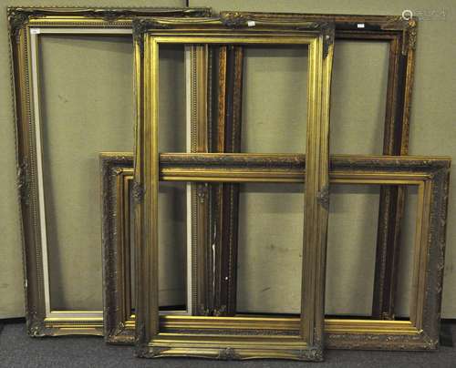 A group of four large gilt picture frames with varying decoration,