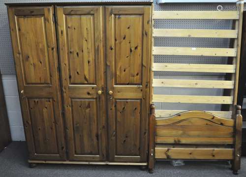 A Ducal three door pine wardrobe, 140cm wide and a pine bed frame,