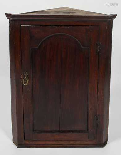 A George III oak corner cupboard with frieze top over an arch panelled door,