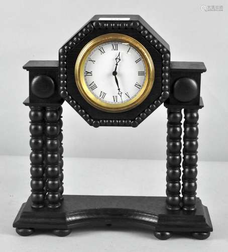 An ebonized mantle clock, with bobbin turned columns and Roman numerals denoting hours,