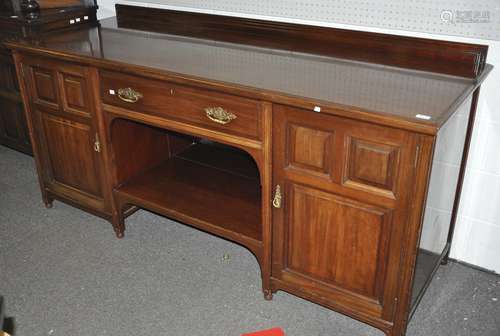 An Edwardian mahogany sideboard with two panel door cupboards flanking a drawer set with brass