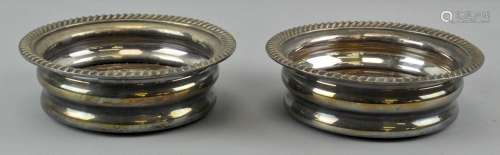 A pair of silver plated wine coasters retailed by Harrod's, mahogany base,
