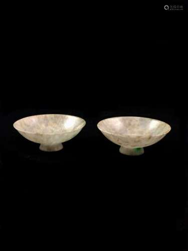 Pair of small cups with flared walls on small heel, in white jadeite with beige veins, with some emerald spots. China, early 20th century. Height 3 cm - Diam. 8.5 cm