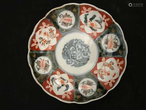 Round porcelain dish with concentric decoration radiating from alternating red and green cartouches, with tea leaves and teapot decoration in the basin, the wing poly-lobed. Japan around 1900. Diameter: 21,5 cm