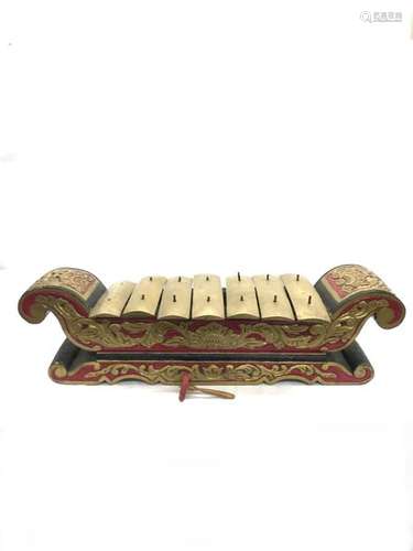 INDONESIA, painted wooden saron carved with rinceaux, bronze blades. Length: 106 cm. Width: 36 cm. Height: 31 cm. Wear and small accidents. A wooden and fabric mallet is attached. Height of the mallet: 16 cm.