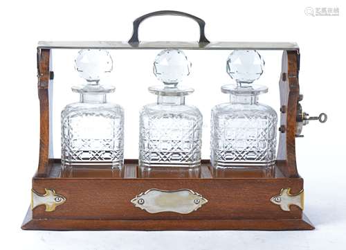 A 20th Century oak Tantalus with silver plated mounts, with three decanters and multifaceted