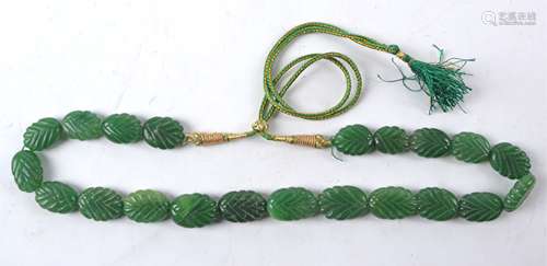 An Asian green hardstone bead necklace each section in the form of a leaf, on a gilt and green