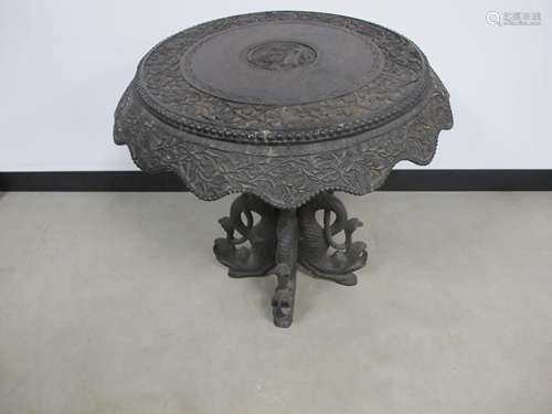 A heavily carved Indian occasional table, circular top with central carving of Monkey and Naga Snake