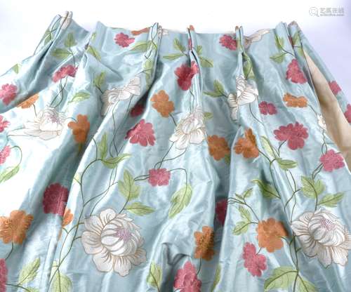 A pair of curtains, in cream, pink orange and green embroidery upon a blue ground, with a cream