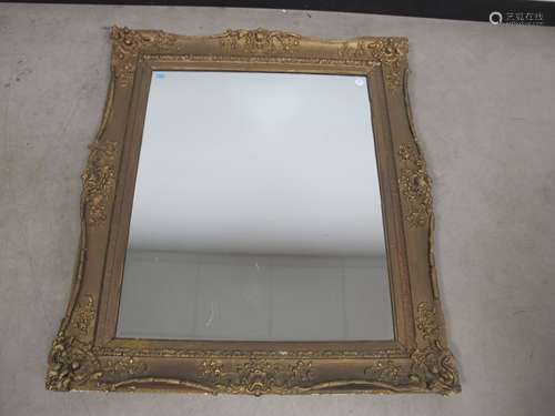 A swept framed wall mirror, antique gilded gesso frame with a contemporary glass plate, 88cm x 100cm