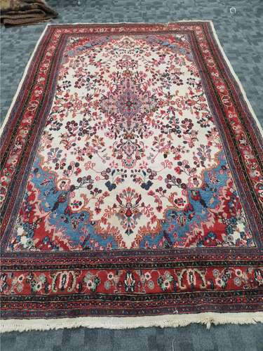 A woollen carpet with central octofoil design and foliate surround, on a cream ground with a red