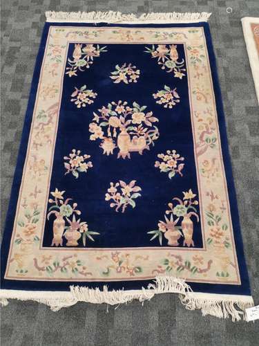 A Peking Oriental rug with precious objects and botanical sprays, on a dark blue ground, with