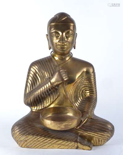 A large brass figure of a cross legged Buddha, seated in the lotus position and holding an empty