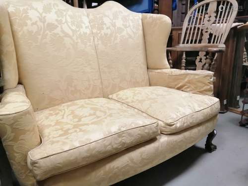 Two seater upholstered wing back settee, set on claw and ball feet to the front. Floor to cushion