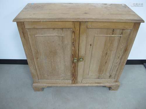 A waxed pine two door cupboard double panelled doors raised on bracket plinth, 93cm x 41cm x 87cm