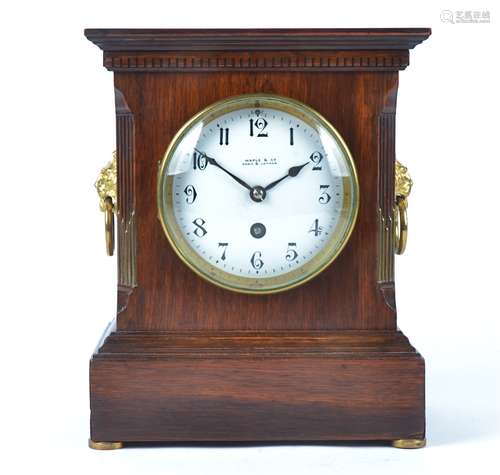 An early 20th century stained oak mantel clock, circular enamel dial with Arabic numerals