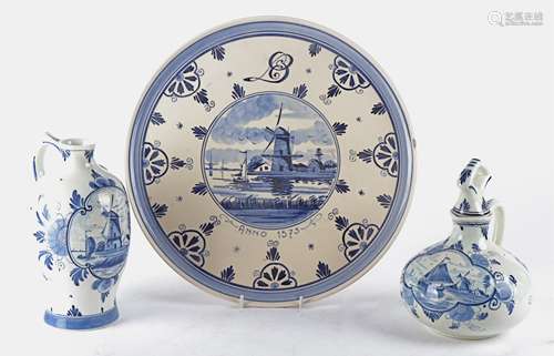 Three pieces of blue and white Delft pottery, two jugs and a plate, each with a cartouche showing