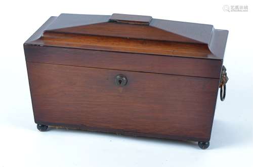 A Regency sarcophagus shaped tea caddy, raised on bun feet, the lid opening to reveal two